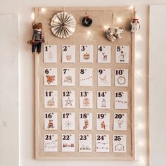 a bulletin board with calendars and ornaments hanging on it's side, in front of a white wall