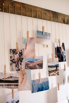 several pictures hanging on clothes pins and pinned to a white wall with wooden pegs