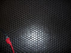 a close up of a metal plate with a red wire on it and a black background