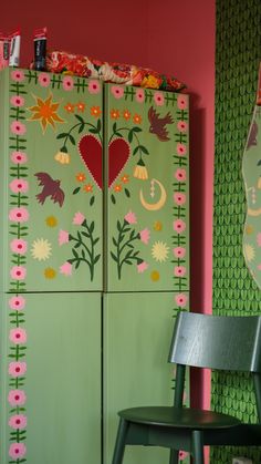 a green cabinet with flowers and hearts painted on it