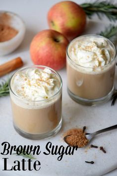 two glasses of brown sugar latte on a plate with cinnamon and apples in the background