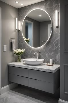 Modern bathroom with a round backlit mirror, gray geometric tile backsplash, and floating vanity with marble countertop. Classic Gray Bathroom, Gray Bathroom Decor Ideas, Bathroom Ideas Grey, Modern Bathroom Design Grey, Gray Bathroom Ideas, Gray Bathrooms, Grey Bathroom Ideas, Monochrome Interior Design, Grey Bathroom Decor