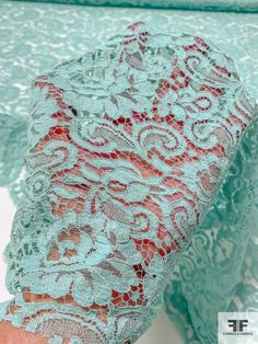 a woman's hand is holding a blue lace fabric