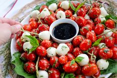 a platter filled with cherry tomatoes and mozzarella sprinkled with basil