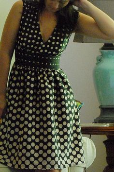 a woman standing in front of a mirror wearing a polka dot dress