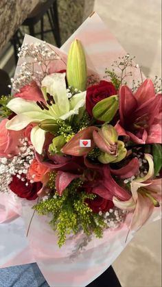 a bouquet of flowers sitting on top of a white and red striped table cloth in someone's hand