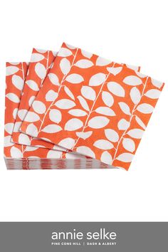 four orange napkins with white leaves on them