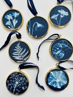 six blue and white flowers are hanging from round gold - plated pendants with ribbon