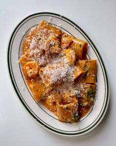 a white plate topped with pasta covered in parmesan cheese