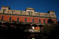 an old red brick building with windows and balconies on the top floor, against a blue sky