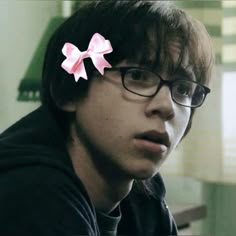 a young man wearing glasses with a pink bow on his head