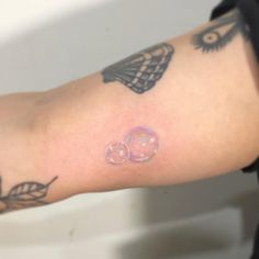 a person with tattoos on their arm holding a doughnut in the shape of a heart