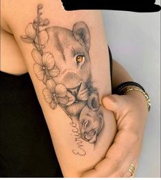 a woman's thigh with a lion and cub tattoo on the side of her leg