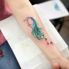 a person with a tattoo on their arm that reads, happy birthday and has a colorful peacock