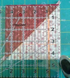 a pair of scissors sitting on top of a cutting mat next to a piece of fabric