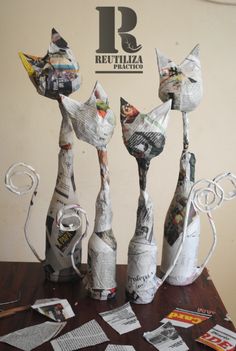 three cats made out of newspaper sitting on top of a table