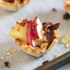 small desserts with apples and other toppings on a baking sheet next to a spatula