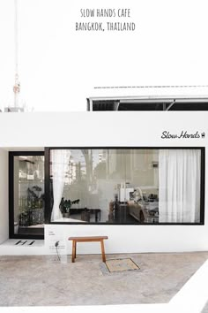 a white building with a bench in front of it and the words slow hands cafe bangkok, thailand