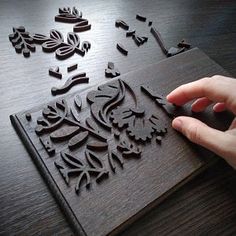 a person is using a mouse to cut out decorative designs on a wooden table top