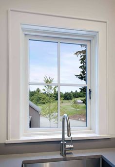 a kitchen sink sitting under a window next to a metal faucet