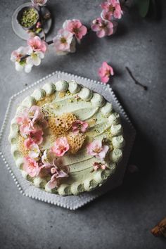 a cake with white frosting and pink flowers on the top sitting on a plate