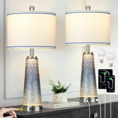 two lamps sitting on top of a table next to a wall mounted phone charger