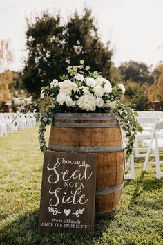 a sign that says choose a seat not a side next to a barrel with flowers