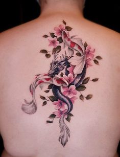 the back of a woman's tattoo with flowers and a dragon