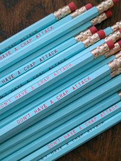 several pencils with writing on them sitting next to each other in front of a wooden table