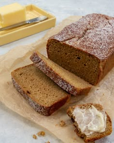 sliced loaf of bread sitting on top of a piece of wax paper next to butter