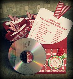 a cd is sitting on top of a red envelope with papers and ribbons around it