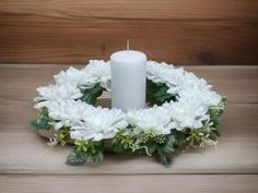 a white candle is sitting in a wreath