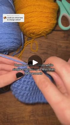 someone is crocheting yarn with scissors on a wooden table next to balls of yarn