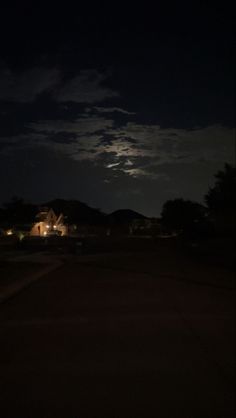 the moon is shining brightly in the night sky over houses and trees on a dark street