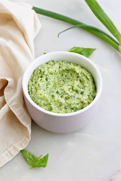 a white bowl filled with guacamole on top of a table next to a napkin