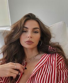 a woman in a red and white striped shirt is sitting on a couch with her hand under her chin