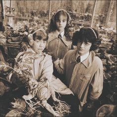 an old photo of three children holding vegetables