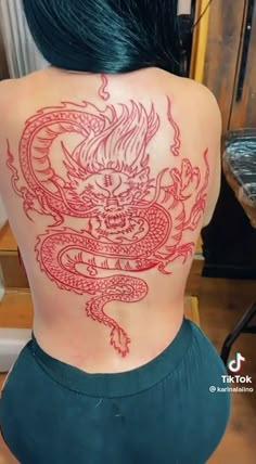 the back of a woman's body is covered in red ink with a dragon on it