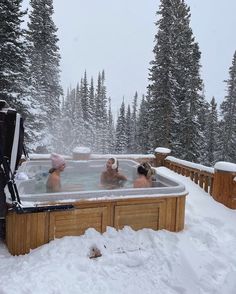 three people in a hot tub surrounded by snow