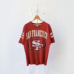 90s San Francisco 49ers NFL t-shirt/ L * PLEASE READ BEFORE PURCHASE * PLEASE consider the PHOTOS before making the decision * The images may DIFFER in appearance from the actual product because we took pictures under daylight.  * PLEASE send your PHONE NUMBER after your purchase for the shipping company to contact you X No returns X No refund Condition : 9/10 More details : tear (sleeve)/ look at the pictures  Brand : Pro player Size : L Pit to pit/ Chests : 23/46 inches  Length : 30.5 inches  Material : cotton  Color : red * ALL ITEMS are VINTAGE which may show some signs of wear and tear * Due to the different display and different light, the picture may not reflect the actual color of the item * Please, remember that our items are vintage so they may show some signs of wear, tear and y Vintage 49ers Shirt, 49ers Outfit, 49ers Shirts, Nfl T Shirts, Athletic Sweatshirts, Shipping Company, San Francisco 49ers, Phone Number, San Francisco