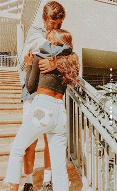 two people embracing each other while standing on the side of a staircase with their arms around each other