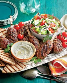 an assortment of meat skewers and salad on a platter