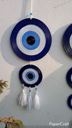 three blue and white plates hanging on the wall with tassels attached to them