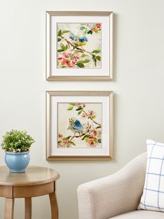 two framed pictures hang on the wall next to a small table with a potted plant