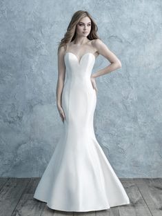 a woman in a white wedding dress standing on a wooden floor