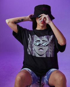 a woman sitting on top of a skateboard wearing a black shirt with a graphic