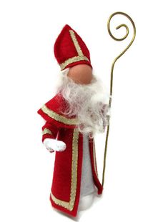 a red and white santa clause doll with a cane in his hand on a white background