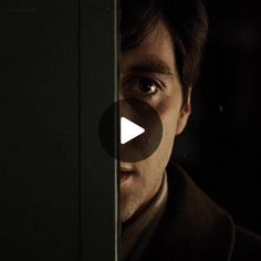 a man looking out from behind a door in the dark with an evil look on his face