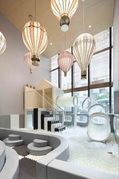 an indoor play area with white furniture and lights hanging from the ceiling