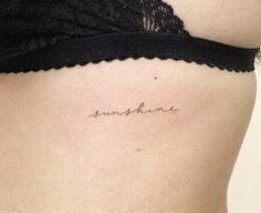 a woman's stomach with the word sunshine tattooed on her lower side ribcage